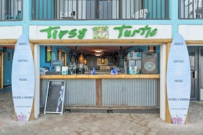 A storefront with a sign reading 'Tippy Turtle' and surfboards on either side. - Landmark 1048- 1BR/1.5BA-Indoor/Outdoor Pools (Myrtle Beach)