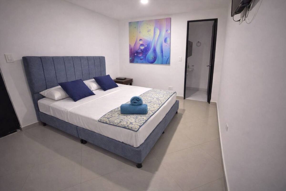 A bedroom with a bed, pillows, a blanket, and a wall art piece.
