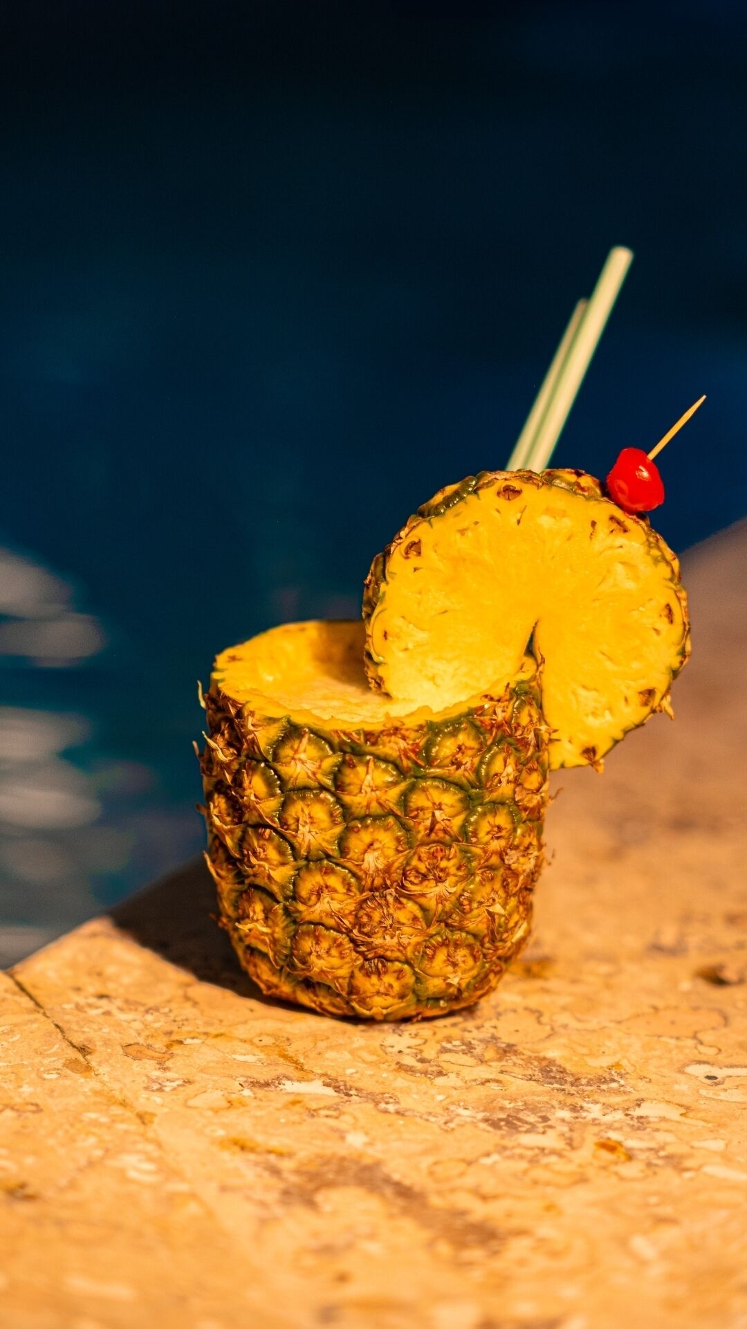 Ein Cocktail mit Ananas in einem Glas, mit einer roten Kirsche am Spieß.