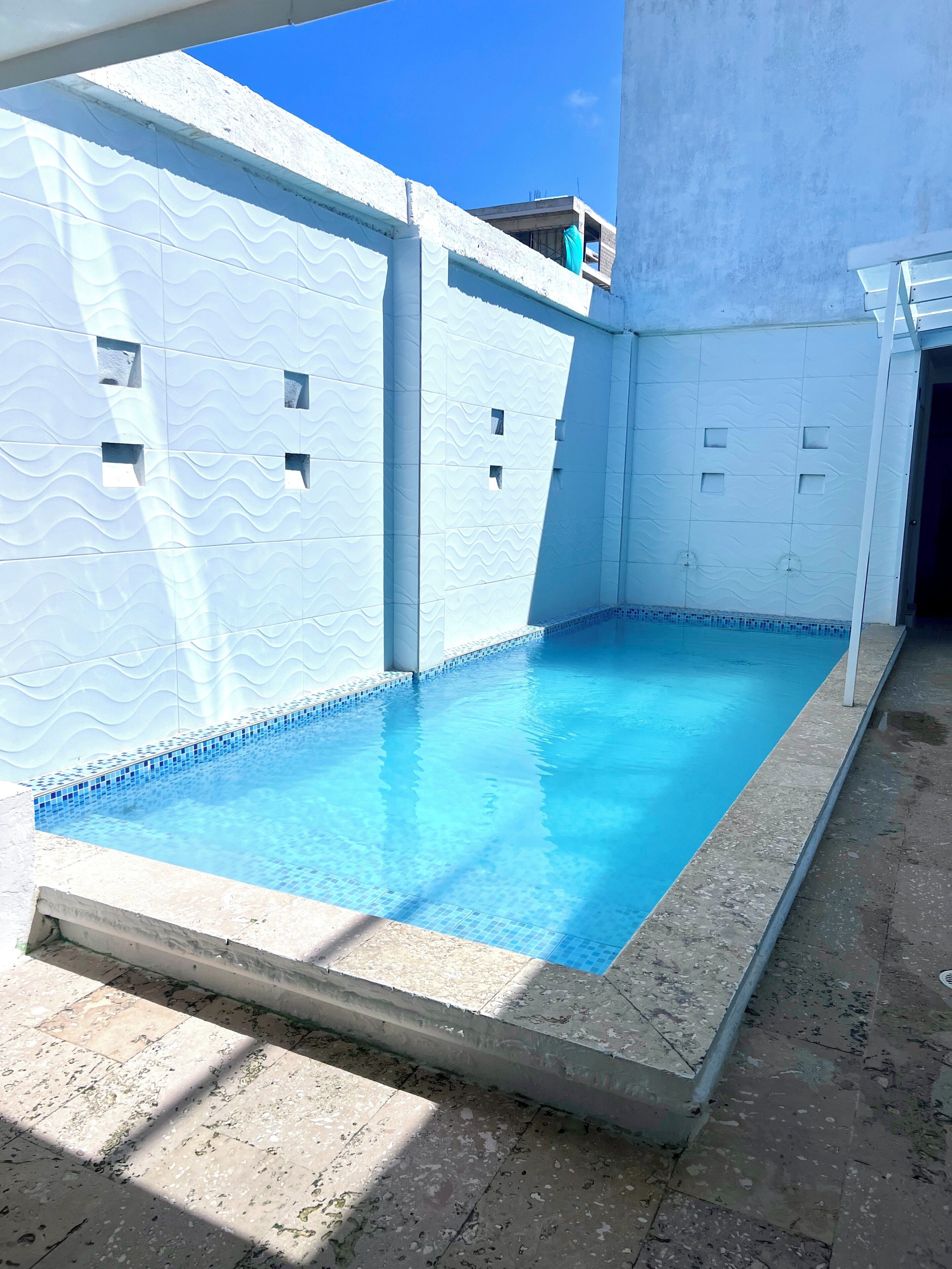 A swimming pool with a tiled edge and a concrete deck.