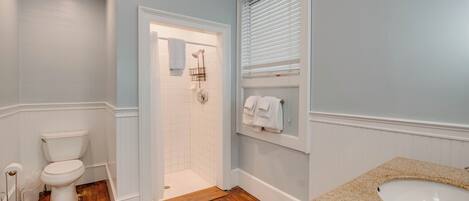 A bathroom with a toilet, shower, and sink.
