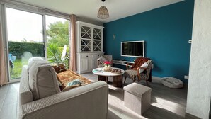 Ein Wohnzimmer mit Sofa, Couchtisch und Sessel, einem Fernseher und einem Schrank.