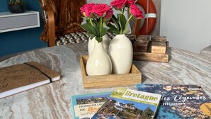 Ein runder Marmortisch mit einem Notizbuch, zwei weißen Vasen mit rosa Blumen und einem Bücherstapel.