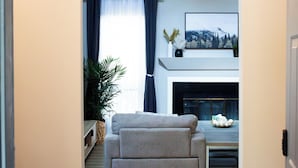 A living room with a sofa, a fireplace, and a welcome sign.