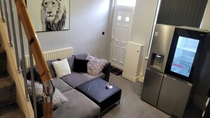 A modern living room with a sofa, a television, and a radiator. - Apartment - Sleeps 5 - Great Location - Parking (Stoke-on-Trent)