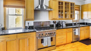 A kitchen with wooden cabinets, a stainless steel range hood, a built-in oven, and a granite countertop. - Urban San Francisco Retreat: Stunning City Views! (San Francisco)