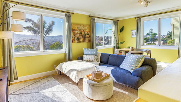 A bright living room with a sofa, ottoman, and a painting on the wall. - Urban San Francisco Retreat: Stunning City Views! (San Francisco)