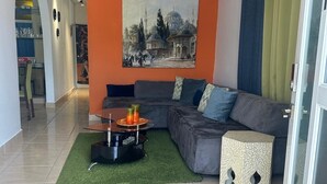 Una sala de estar con un sofá modular, una mesita redonda con una vela y un cuadro en la pared.