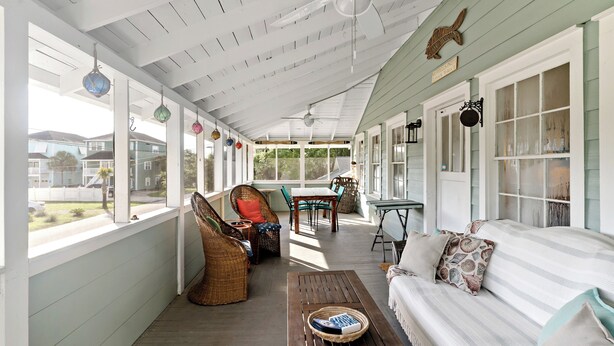 A covered porch with wicker furniture, a wooden table, and a striped sofa. - Your Ultimate Coastal Retreat! 5 bedroom, 4 bathroom home in Murrells Inlet, SC! (Murrells Inlet)