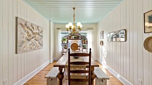 A dining area with a wooden table and benches, a chandelier, and artwork on the walls. - Your Ultimate Coastal Retreat! 5 bedroom, 4 bathroom home in Murrells Inlet, SC! (Murrells Inlet)