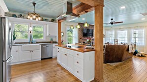 A spacious kitchen with white cabinetry, a wooden island, and a brick accent wall. - Your Ultimate Coastal Retreat! 5 bedroom, 4 bathroom home in Murrells Inlet, SC! (Murrells Inlet)