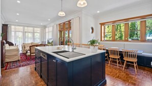 A spacious kitchen with a central island, wooden flooring, and large windows offering natural light. - Spacious heritage home (Moonee Ponds)