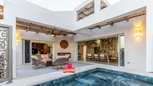 Un área de piscina moderna al aire libre con sillones de descanso, jacuzzi y comedor.