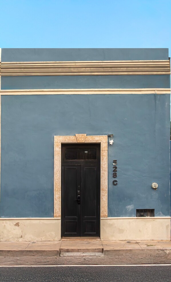 A building facade with a black double door, a small window, and a mailbox.