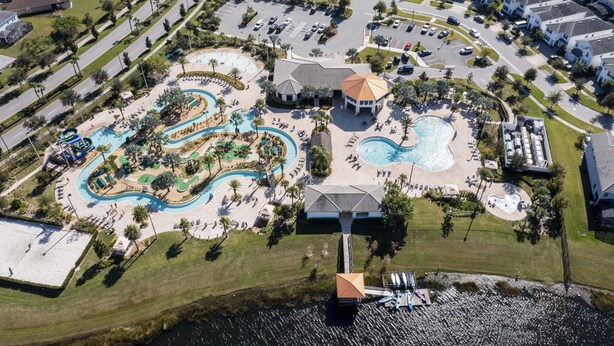 An aerial view of a resort with multiple swimming pools, a central gazebo, and a marina.