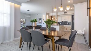 A modern dining area with a wooden table, grey chairs, and pendant lighting.