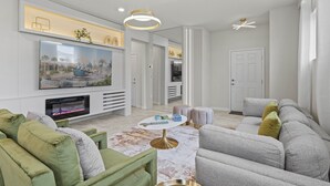 A modern living room with a flat-screen TV, a fireplace, a round coffee table, and a grey sofa.