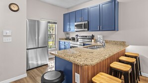 Eine moderne Küche mit blauen Schränken, Edelstahlgeräten und einer Arbeitsplatte aus Granit.