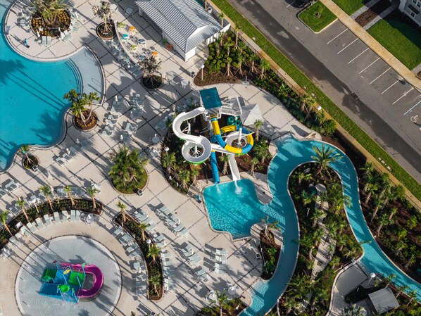 An aerial view of a resort with a large pool, water slides, and lounge areas.