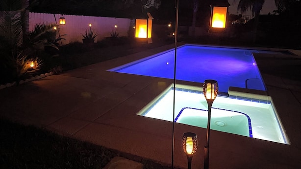 A swimming pool with a blue illuminated edge, surrounded by a paved deck and palm trees. - Casa Colibrí
UltraWIFI, HOTTUB, POOL, PLAYPEN, 2KING BEDS, MULTI FAMILY FRIENDLY (Harlingen)