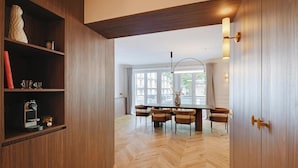 Ein moderner Essbereich mit Holzdielen im Fischgrätmuster, einem runden Tisch mit vier Stühlen und einem Bücherregal mit Dekorationselementen.