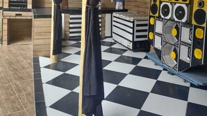 Une pièce avec un sol à carreaux, un meuble noir et blanc, un rideau noir et un système de haut-parleurs PAREDAO CASA.