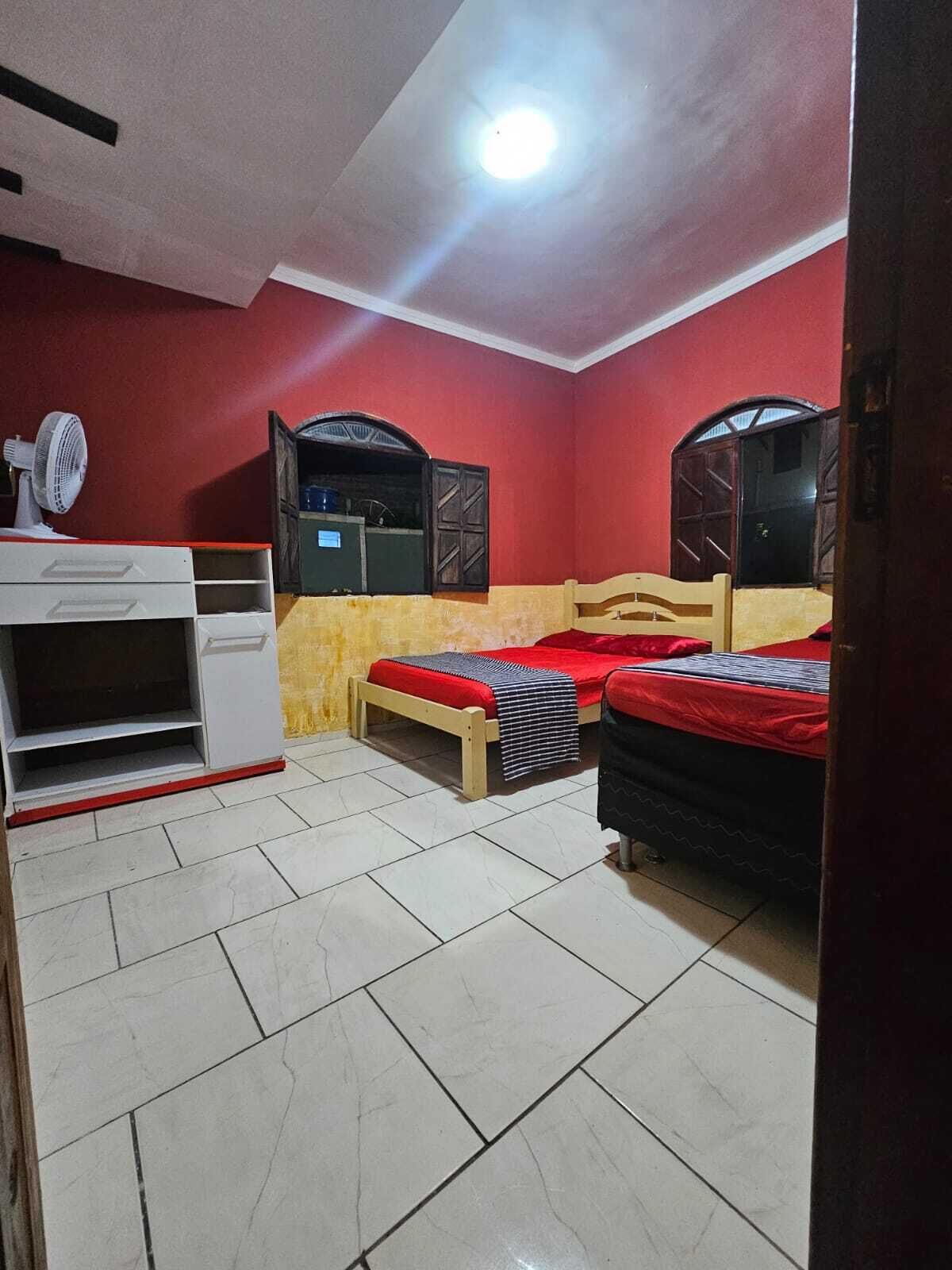 A bedroom with two beds, a white wardrobe, a mirror, and a ceiling light.