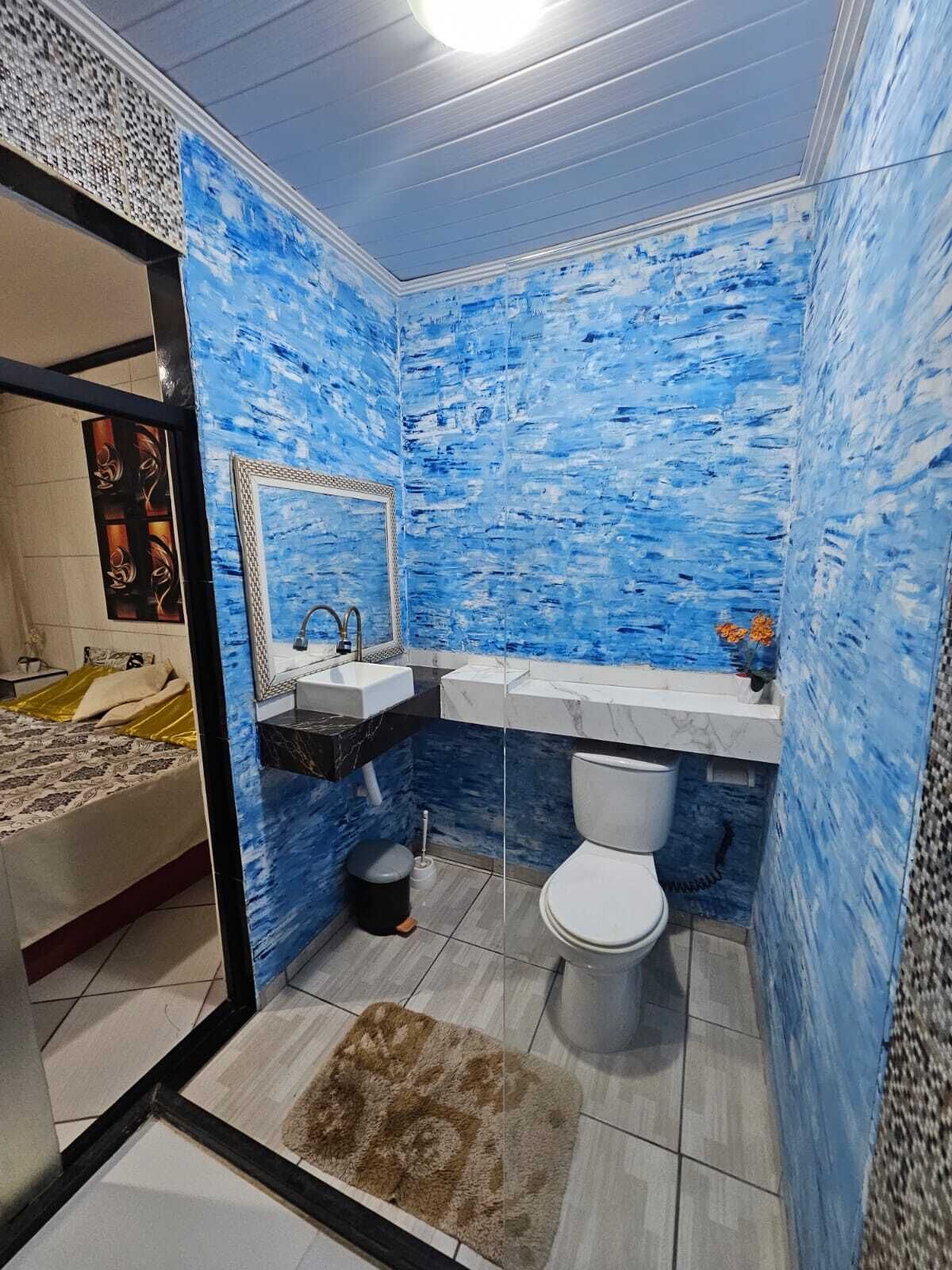 Un baño con paredes azules con textura, un inodoro blanco, un lavamanos y un espejo.
