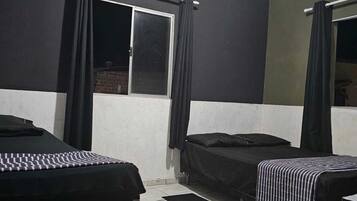 Ein Zimmer mit zwei Betten, einem fensterbelaubten Fenster und einem Fliesenboden.