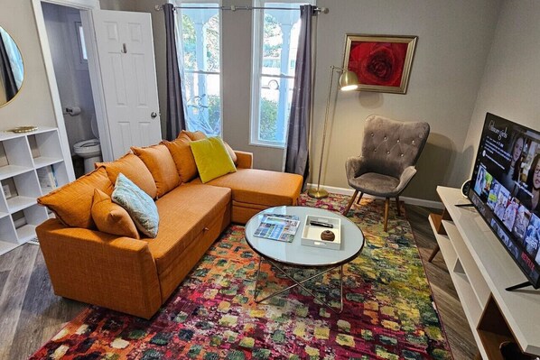 A living room with a sofa, armchair, coffee table, and a TV.