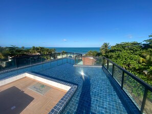 Ein Pool ohne Ende mit freiem Blick auf den Ozean und Palmen.