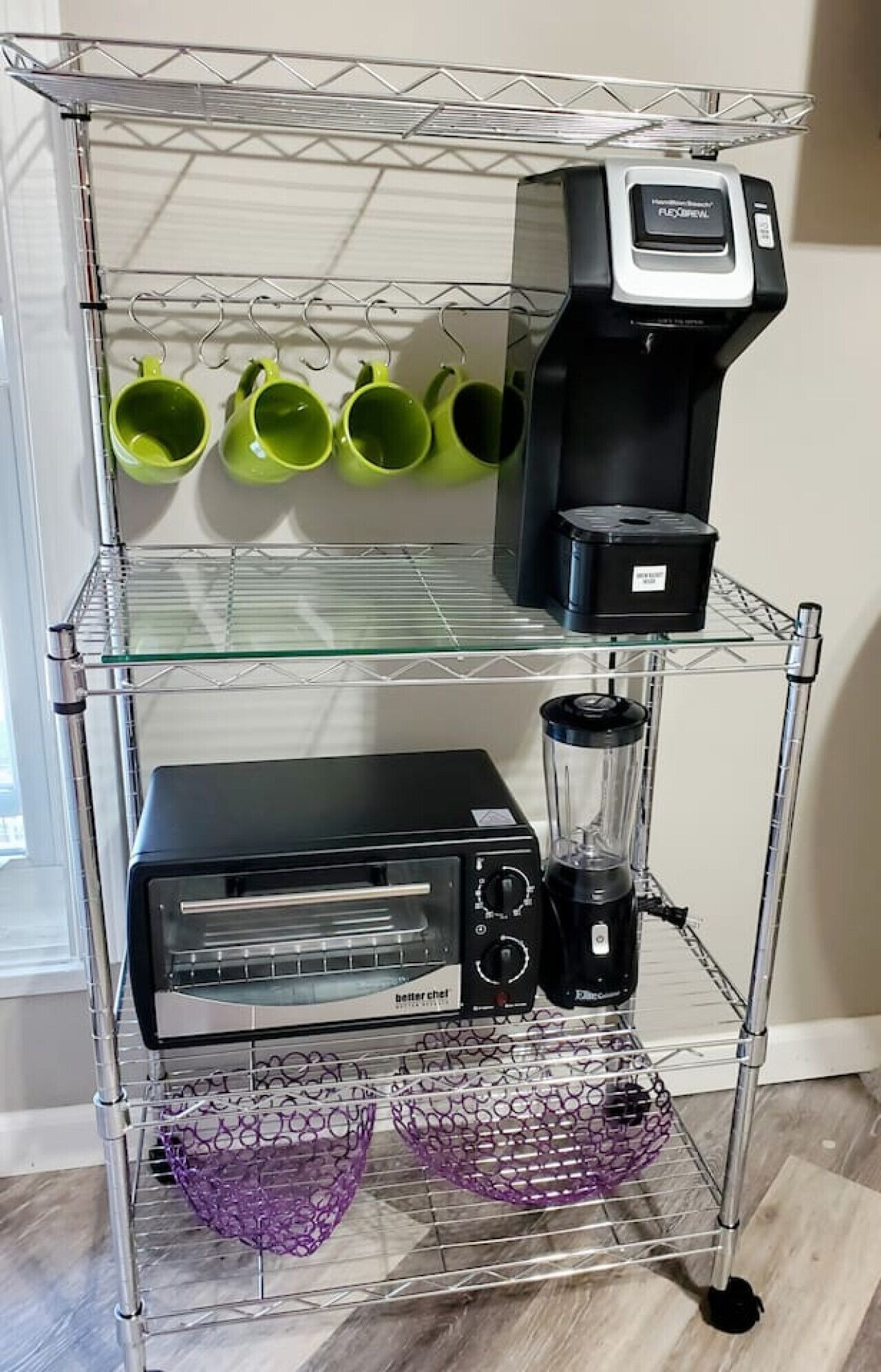 A kitchen cart with a coffee maker, a blender, and green mugs on the top shelf.