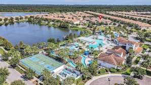 Zona residencial con una gran piscina, canchas de tenis y un lago.