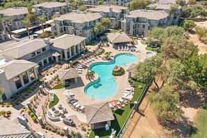 An aerial view of a resort with multiple buildings, a central swimming pool, and outdoor seating areas.