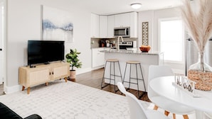 Una cocina moderna con armarios blancos, microondas integrado y una isla grande con taburetes.