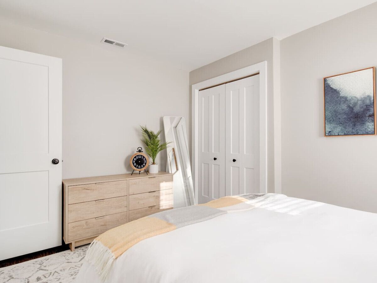 A bedroom with a bed, a dresser, a door, and a painting on the wall.