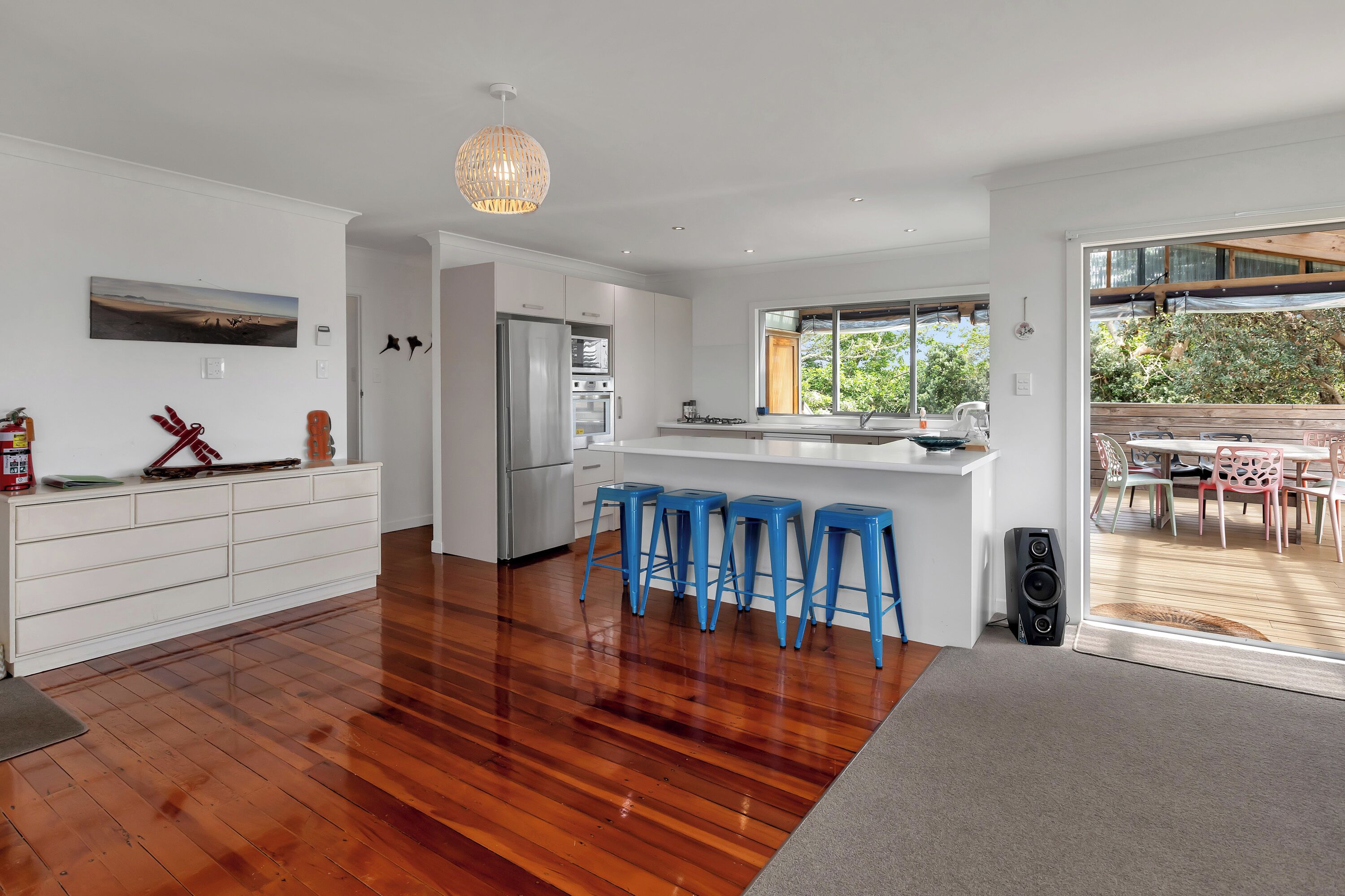 A modern kitchen with white cabinetry, a central island, and blue bar stools.
