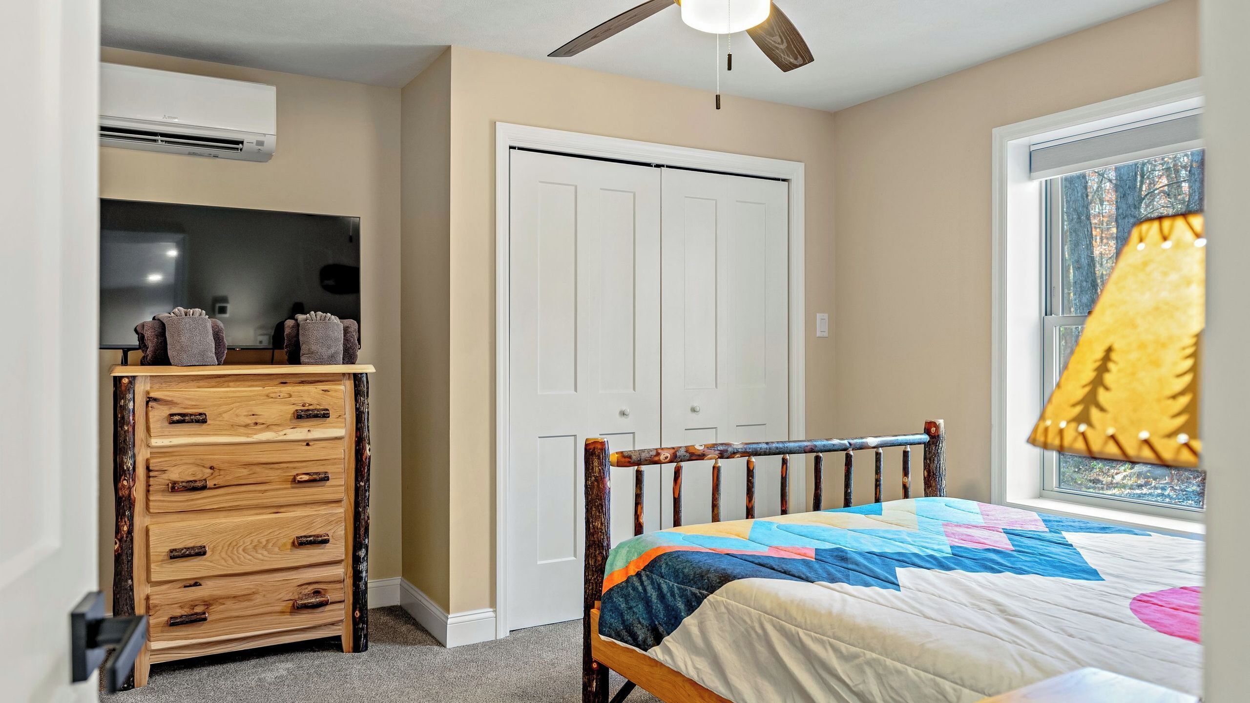 A bedroom with a bed, dresser, closet, and a ceiling fan.