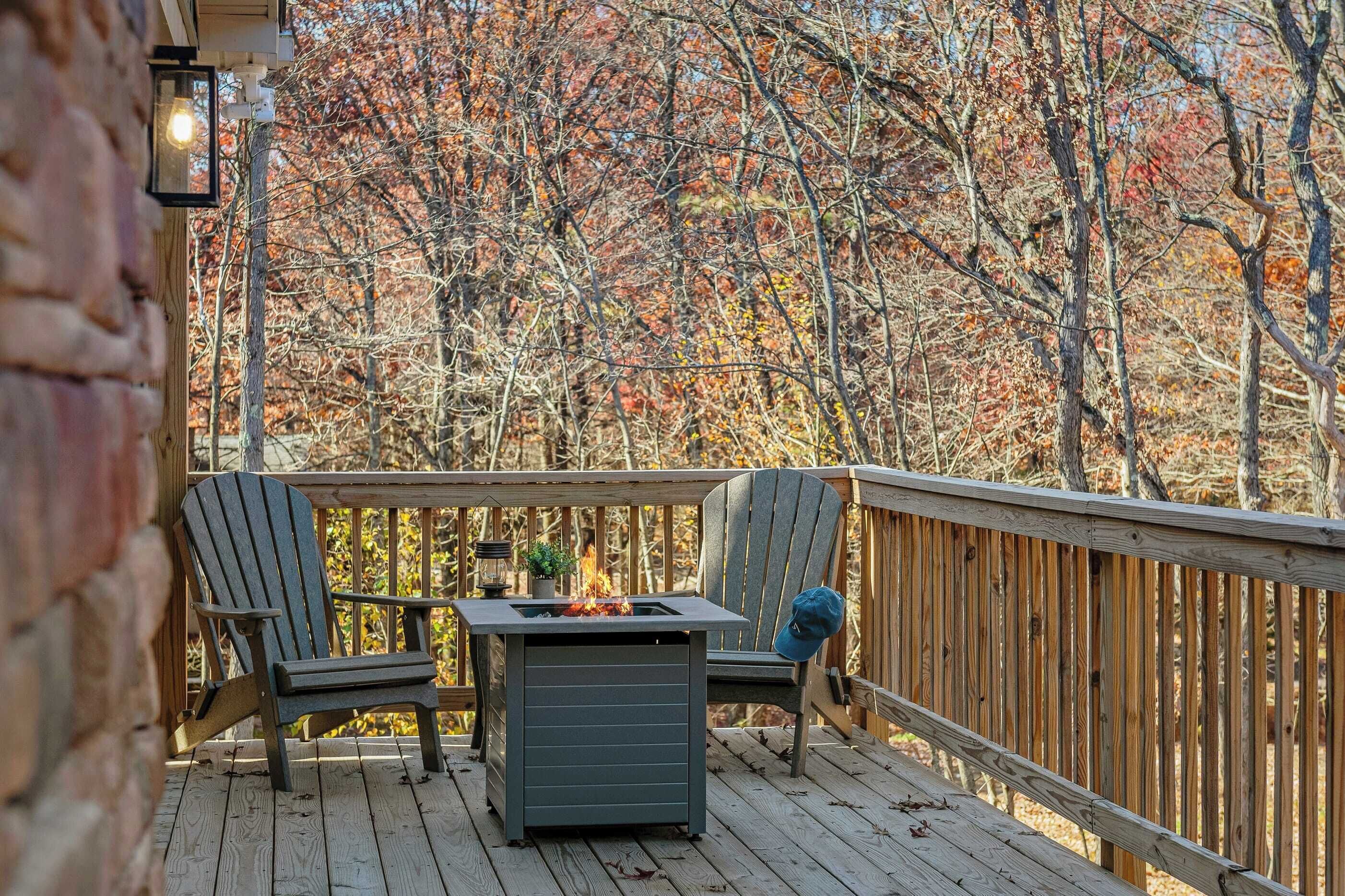Un patio in legno con due poltrone Adirondack e un braciere integrato.
