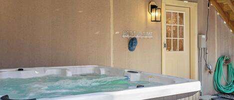 A hot tub in an outdoor setting with a wooden ceiling and a door in the background.