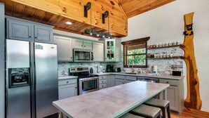 A kitchen with a central island, stainless steel appliances, and a wooden ceiling.
