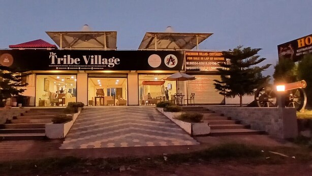 Un edificio llamado 'The Tribe Village' con un cartel que anuncia 'Villas Premium - Cabañas - En venta'.
