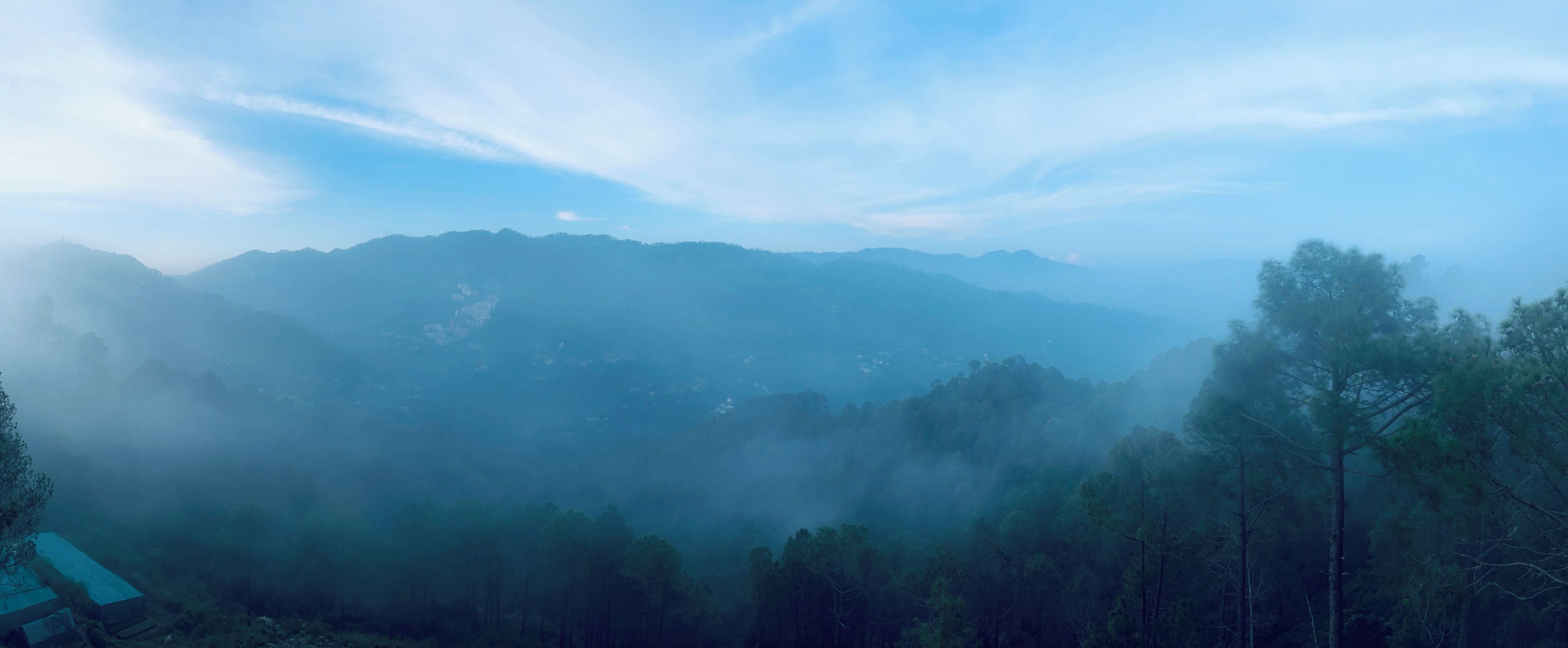 Un paisaje montañoso con bosques densos y cielo despejado.