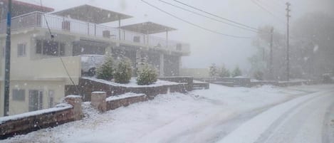 A residential street with houses and a snow-covered road.
