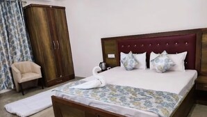 Una cama bien hecha con un almohadón con forma de cisne, un armario de madera, una silla y una colcha estampada.