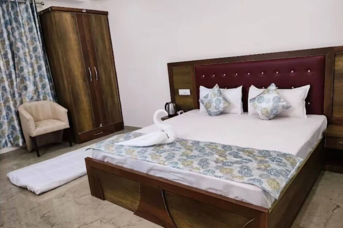 Un lit bien fait, agrémenté d’un oreiller en forme de cygne, d’une armoire en bois, d’une chaise et d’une couvre-lit à motifs.