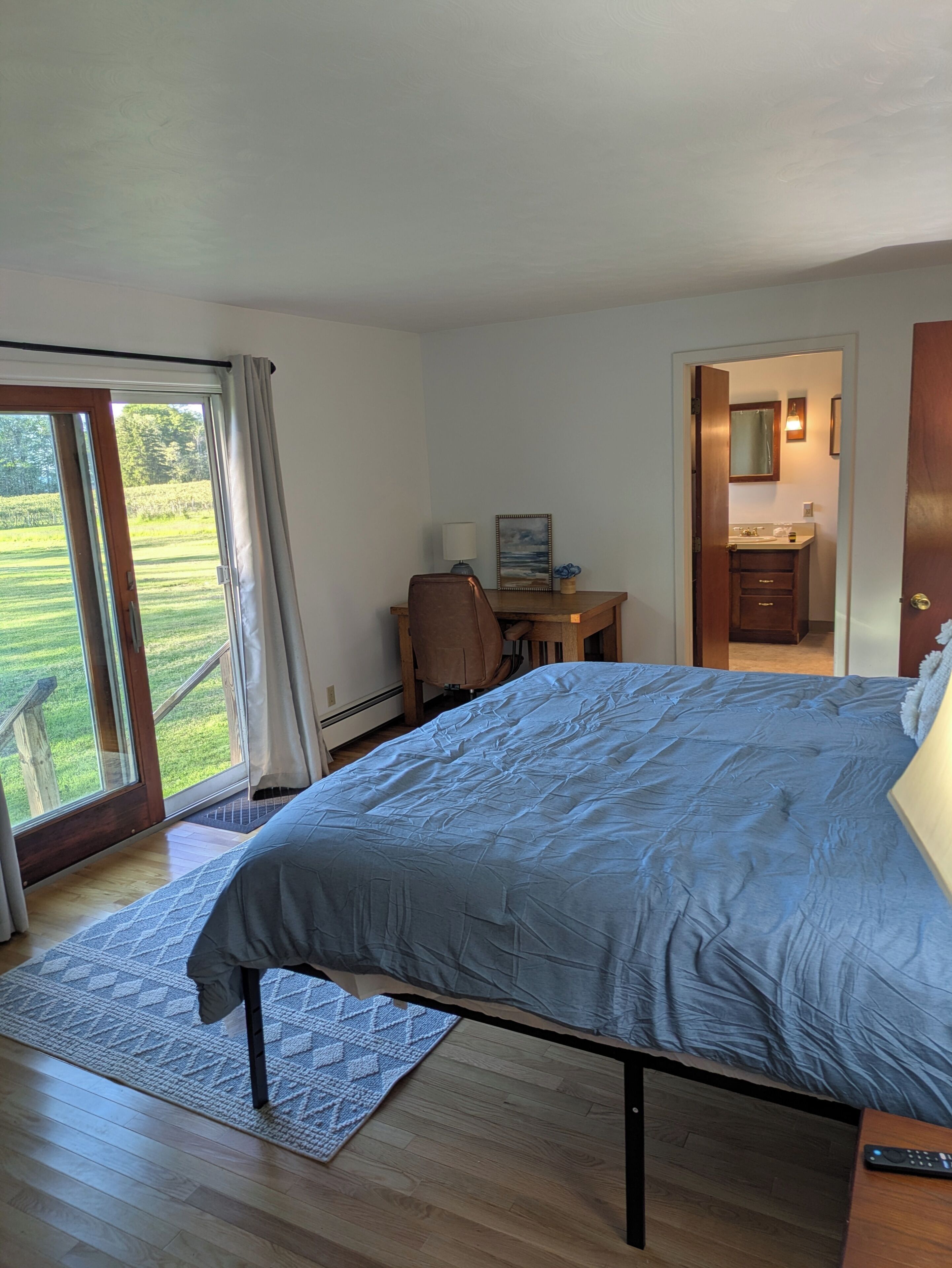 Ein Schlafzimmer mit einem großen Bett, einem Schreibtisch und einem durch eine geöffnete Tür einsehbarer Badezimmer.