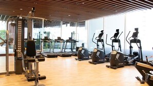 A gym with cardio machines, weight equipment, and large windows.