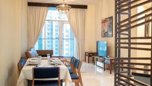 A dining area with a table set for four, a television, and a view of high-rise buildings.
