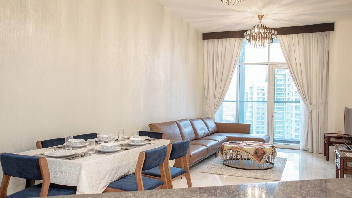 A modern living room with a dining area, a leather sofa, and a chandelier.